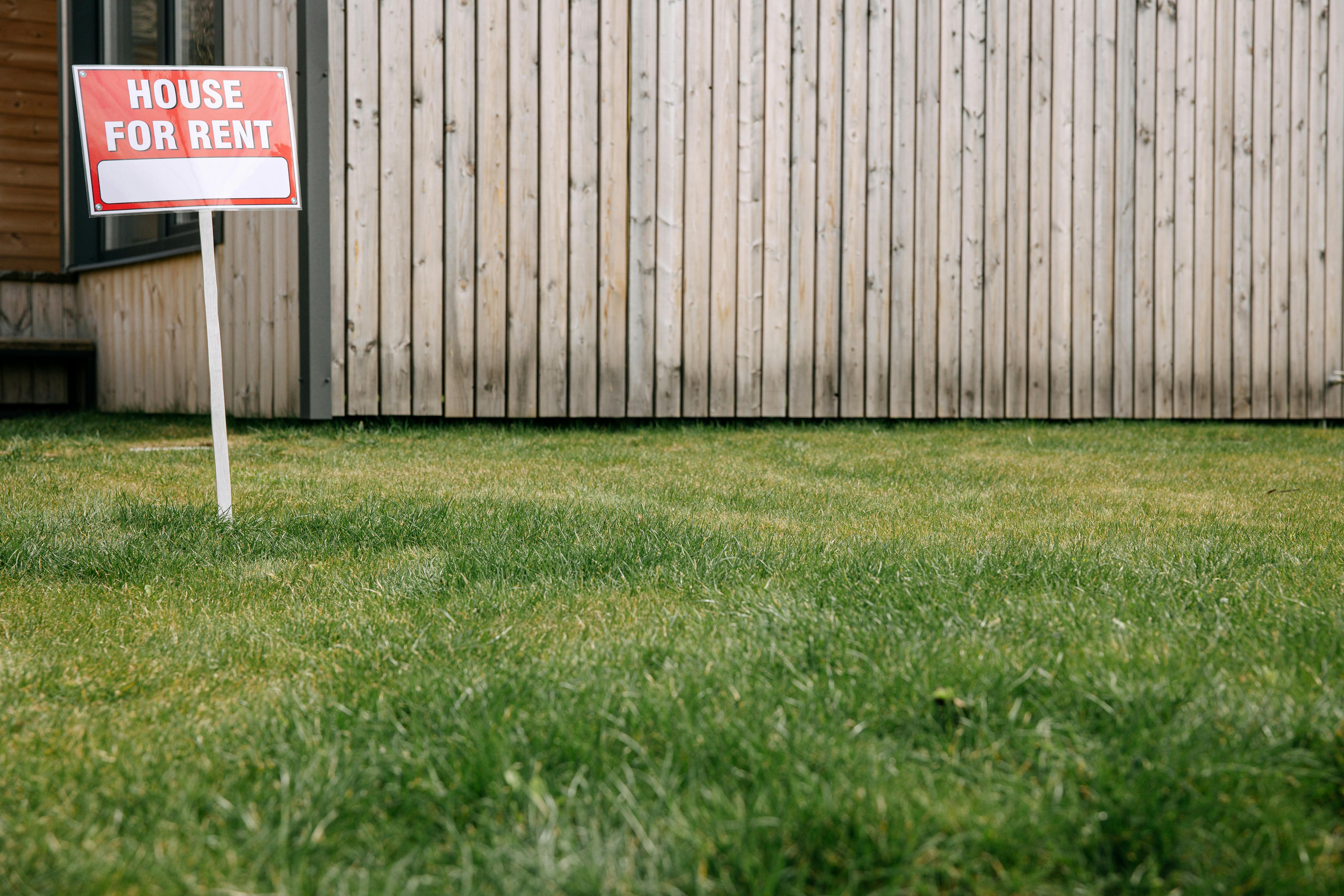 a red and white "for rent" sign in a front yard